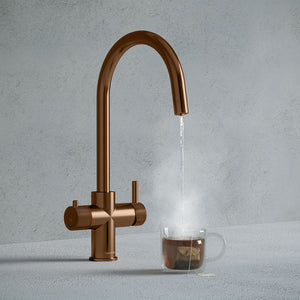 a copper swan neck boiling water tap dispensing hot water to a cup of tea