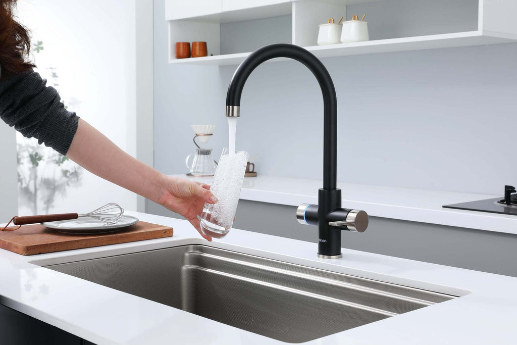 Person washing dishes in a modern kitchen with a black faucet.