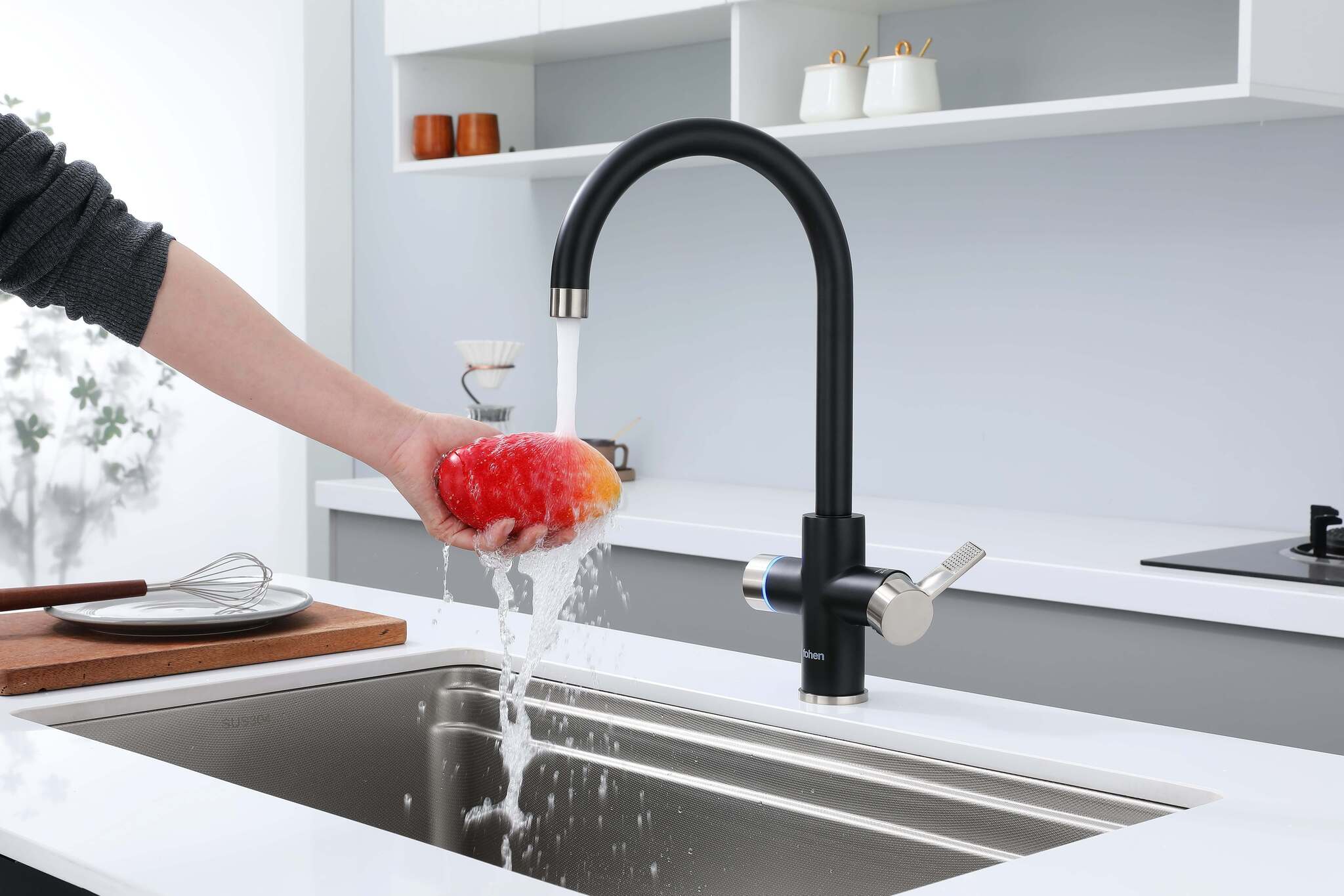Person washing a fruit under a black faucet in a kitchen.