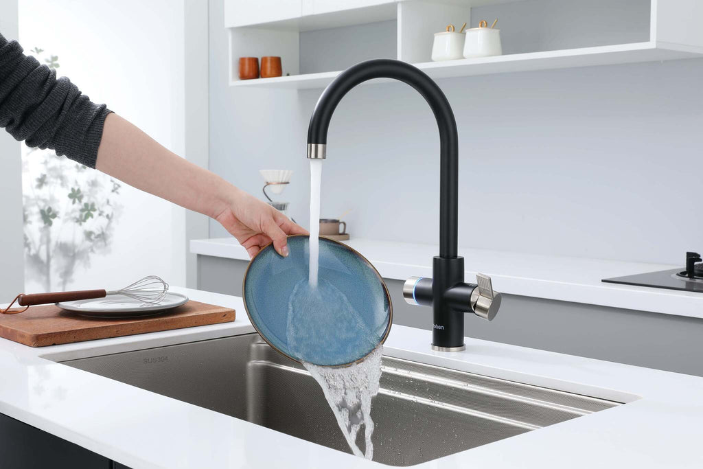 Person washing a blue plate under a black faucet in a modern kitchen.