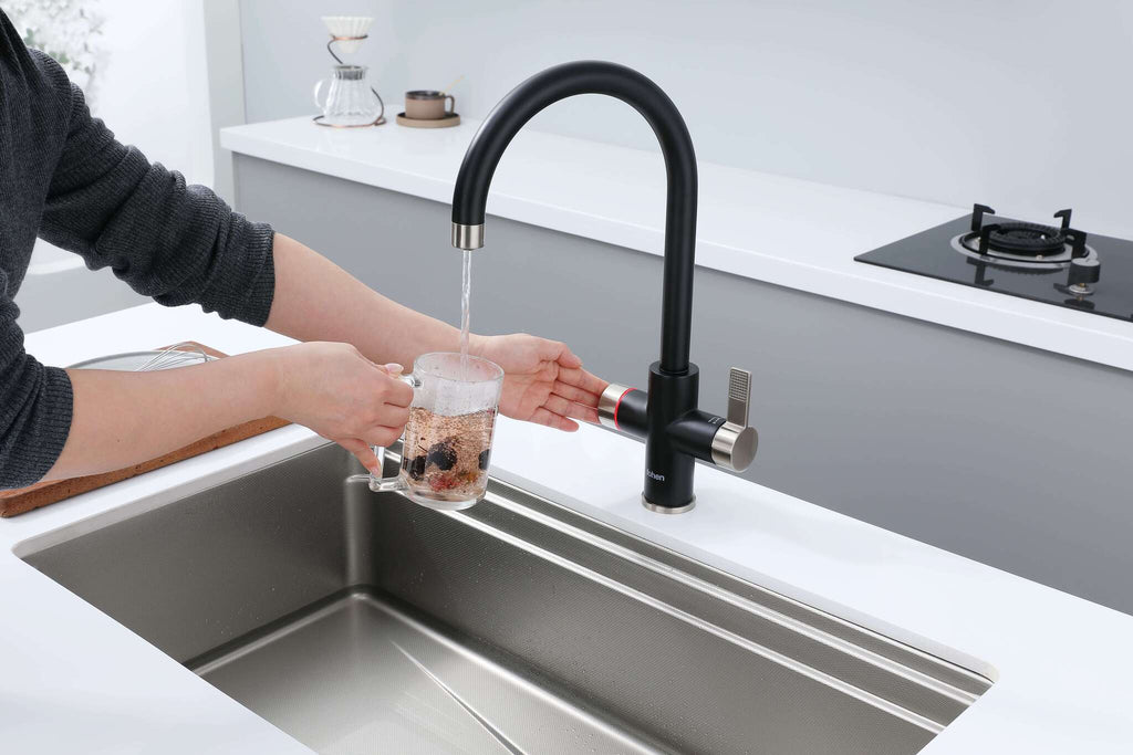 Person filling a glass with water from a modern kitchen faucet.