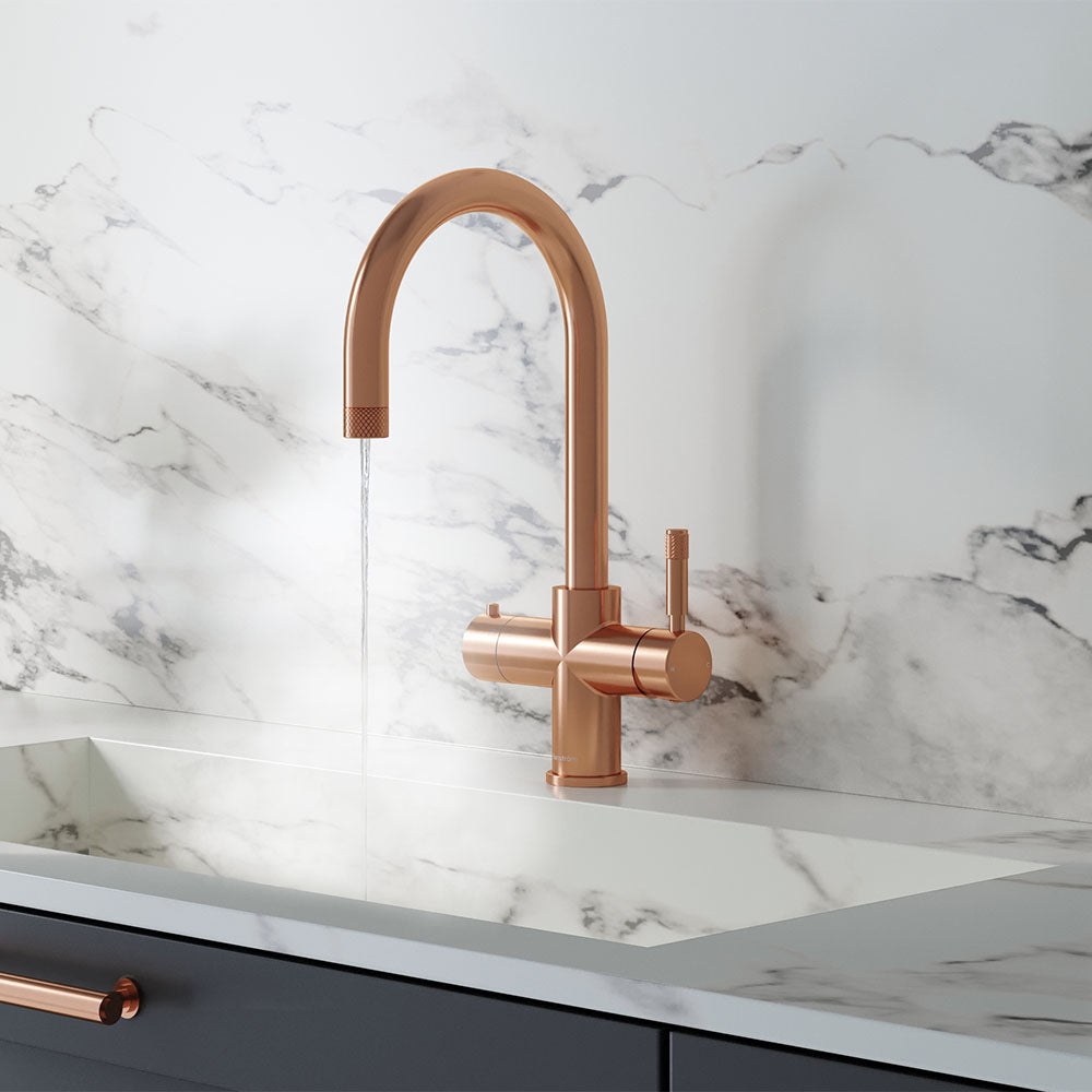 a swan neck rose gold boiling water tap on a white kitchen countertop