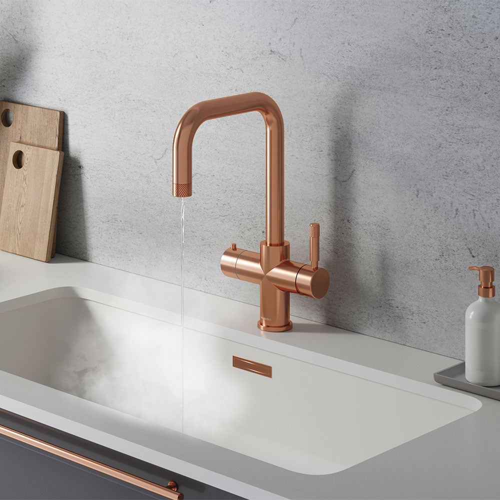 a square-shaped rose gold boiling water tap on a white kitchen countertop