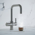 a chrome square-shaped boiling water tap dispensing hot water to a cup of tea