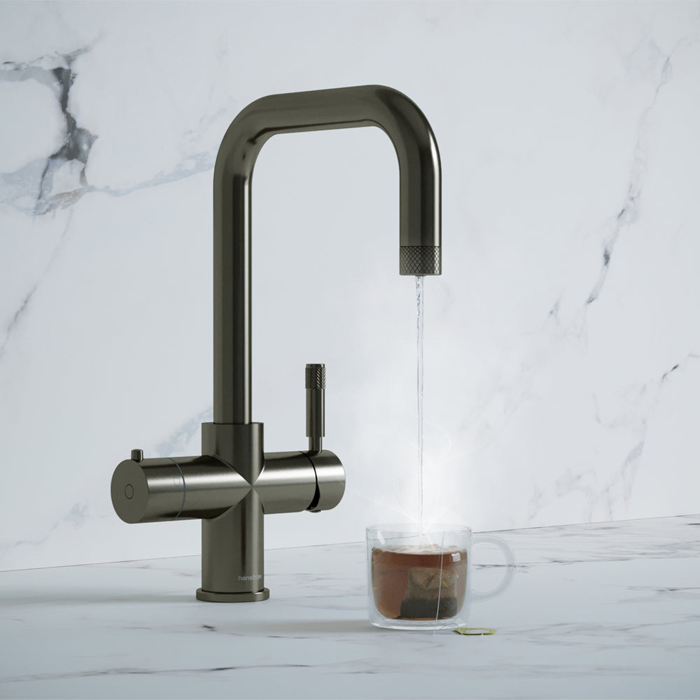 a gunmetal grey square-shaped boiling water tap dispensing hot water to a cup of tea