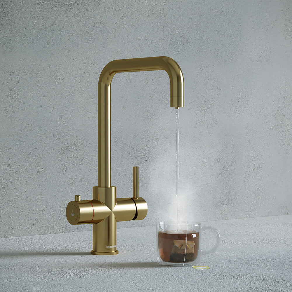 a brushed brass square-shaped boiling water tap dispensing hot water to a cup of tea