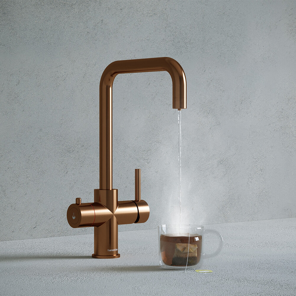 a copper square-shaped boiling water tap dispensing hot water to a cup of tea