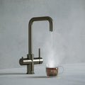 a gunmetal grey square-shaped boiling water tap dispensing hot water to a cup of tea