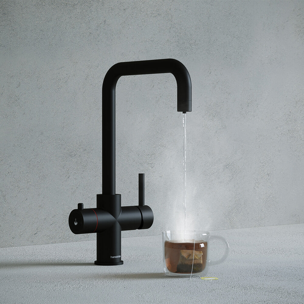 a matt black square-shaped boiling water tap dispensing hot water to a cup of tea