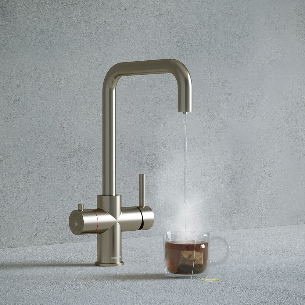 a brushed nickel square-shaped boiling water tap dispensing hot water to a cup of tea