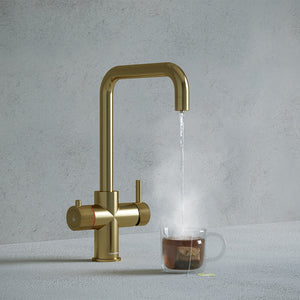 square-shaped brass boiling water tap dispensing hot water to a cup of tea