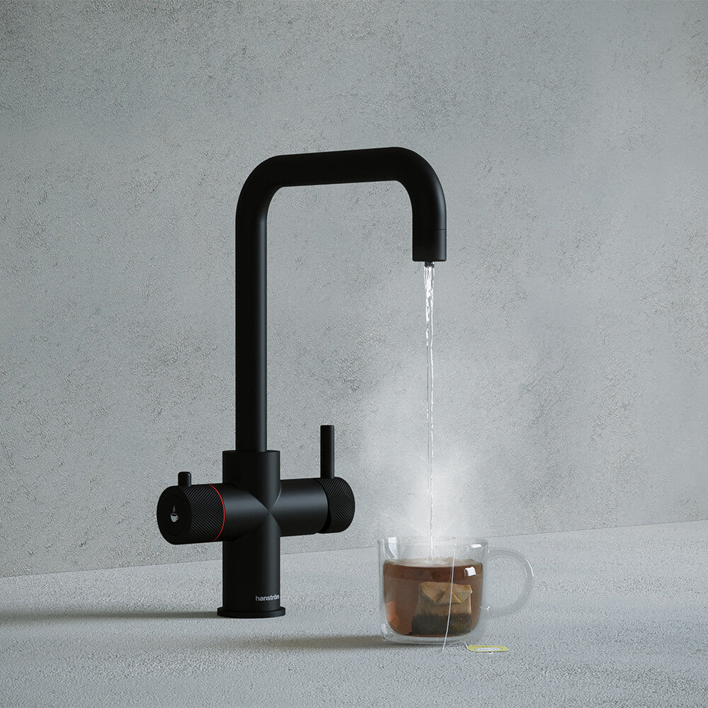 a matt black square-shaped boiling water tap dispensing hot water to a cup of tea