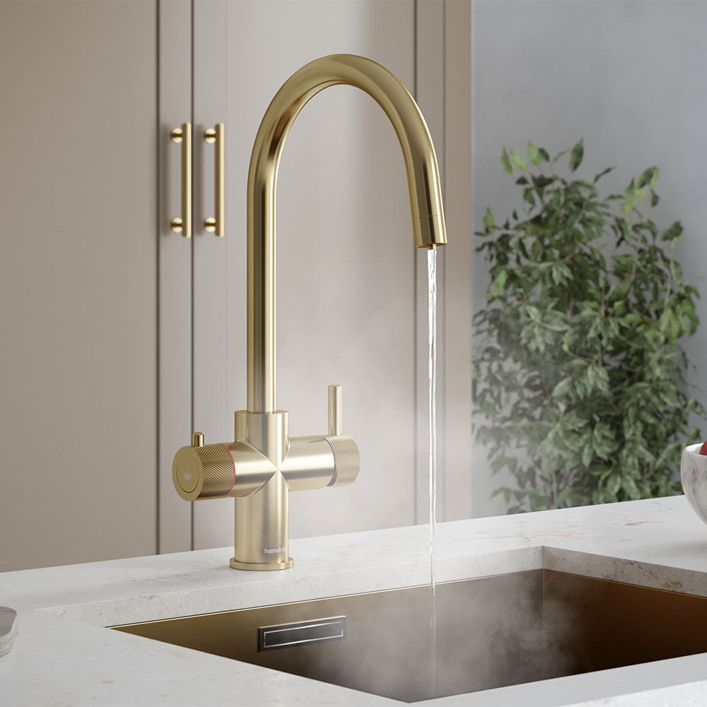 a brushed brass swan neck boiling water tap on a white kitchen countertop