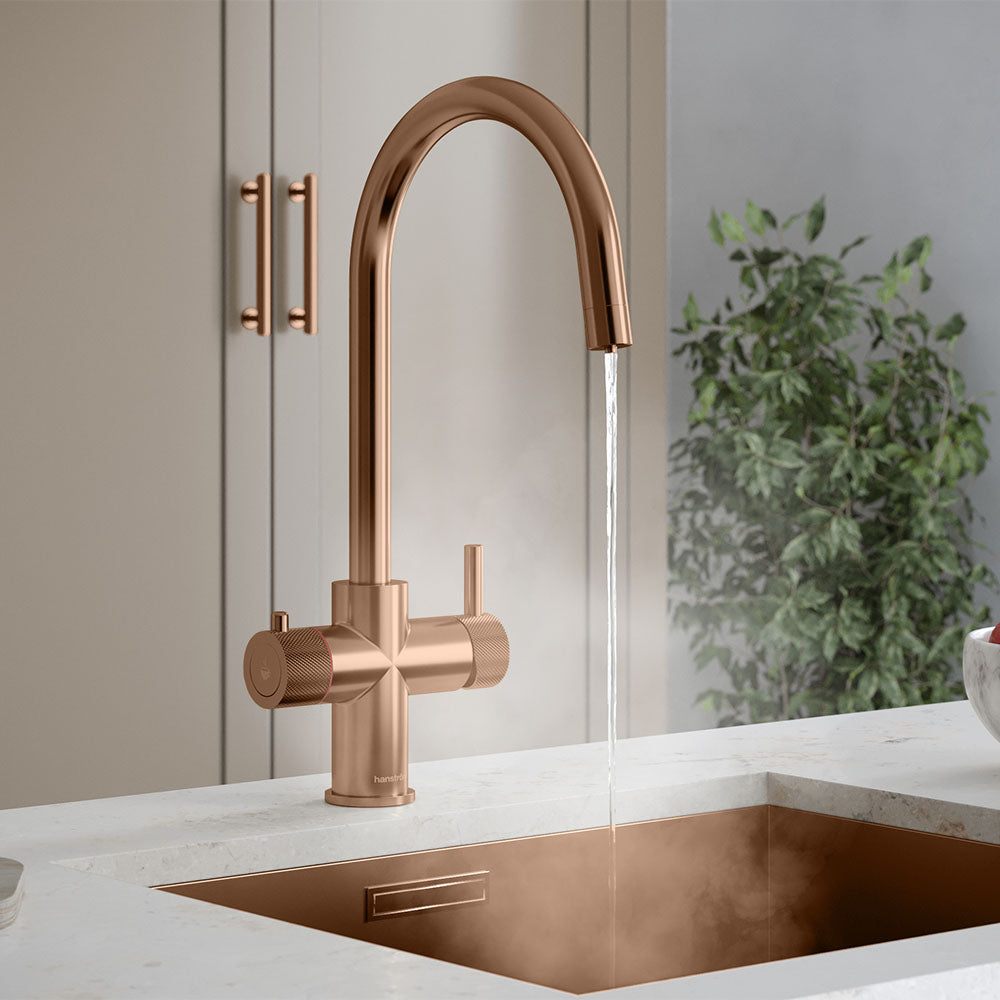 a copper swan neck instant hot tap on a white kitchen countertop