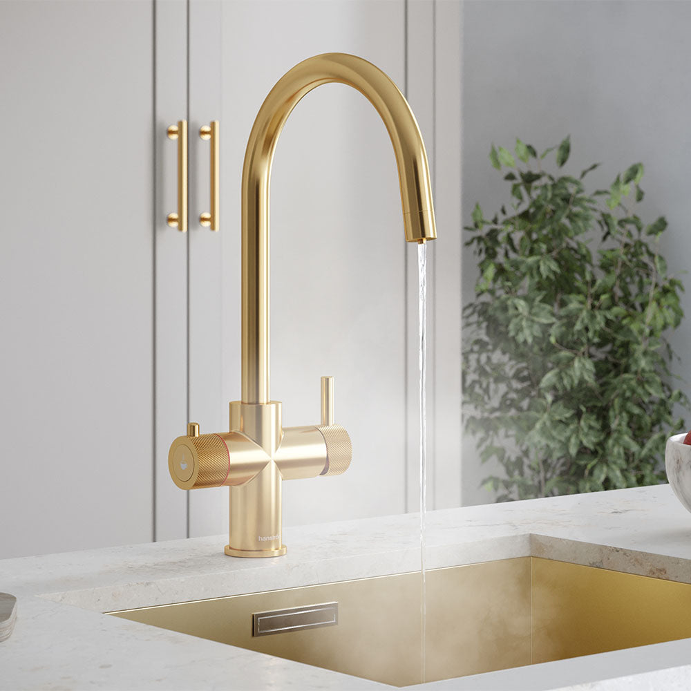 a brushed gold swan neck boiling water tap on a white kitchen countertop